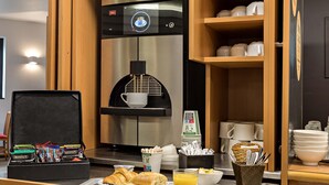 Une kitchenette d’hôtel équipée d’une machine à café, de produits pour le petit-déjeuner et d’un plateau de petit-déjeuner.