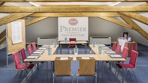 A conference room with a long table, red chairs, and a banner reading 'Premier Best Western.'
