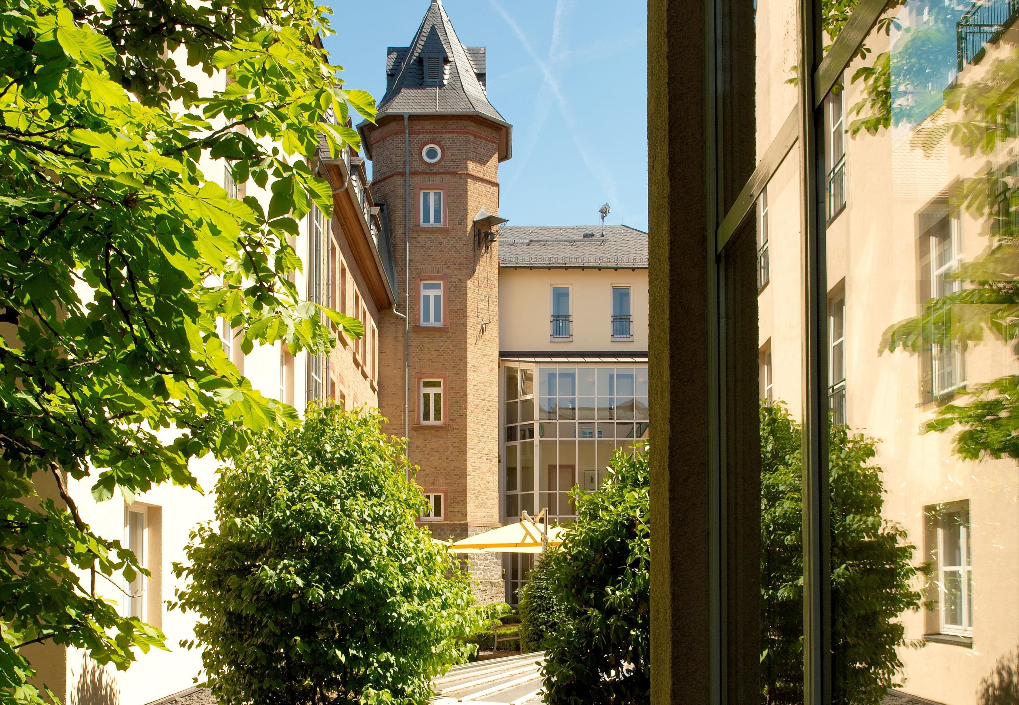 Ein Innenhof mit einem Turm, einem Glasgebäude und Bäumen.