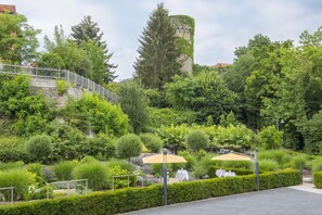 A landscaped garden with a stone wall, trees, and outdoor seating. - Best Western Premier Hotel Villa Stokkum (Hanau)
