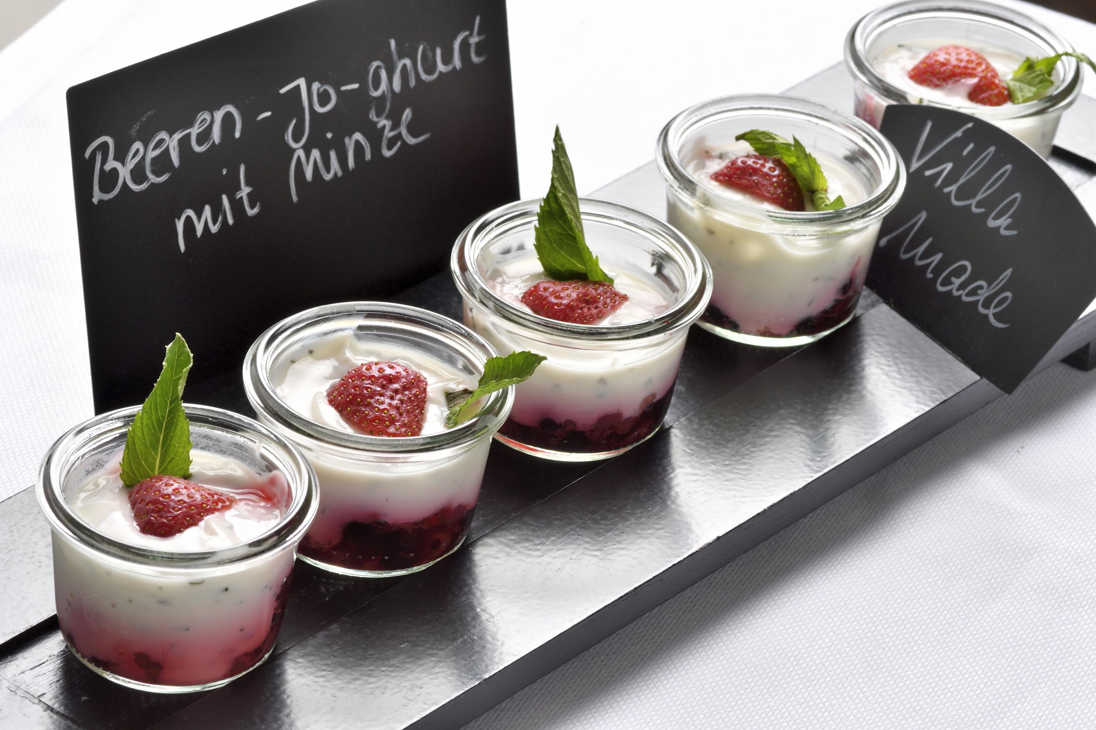A tray of layered desserts with strawberries and mint leaves, accompanied by a sign with text.