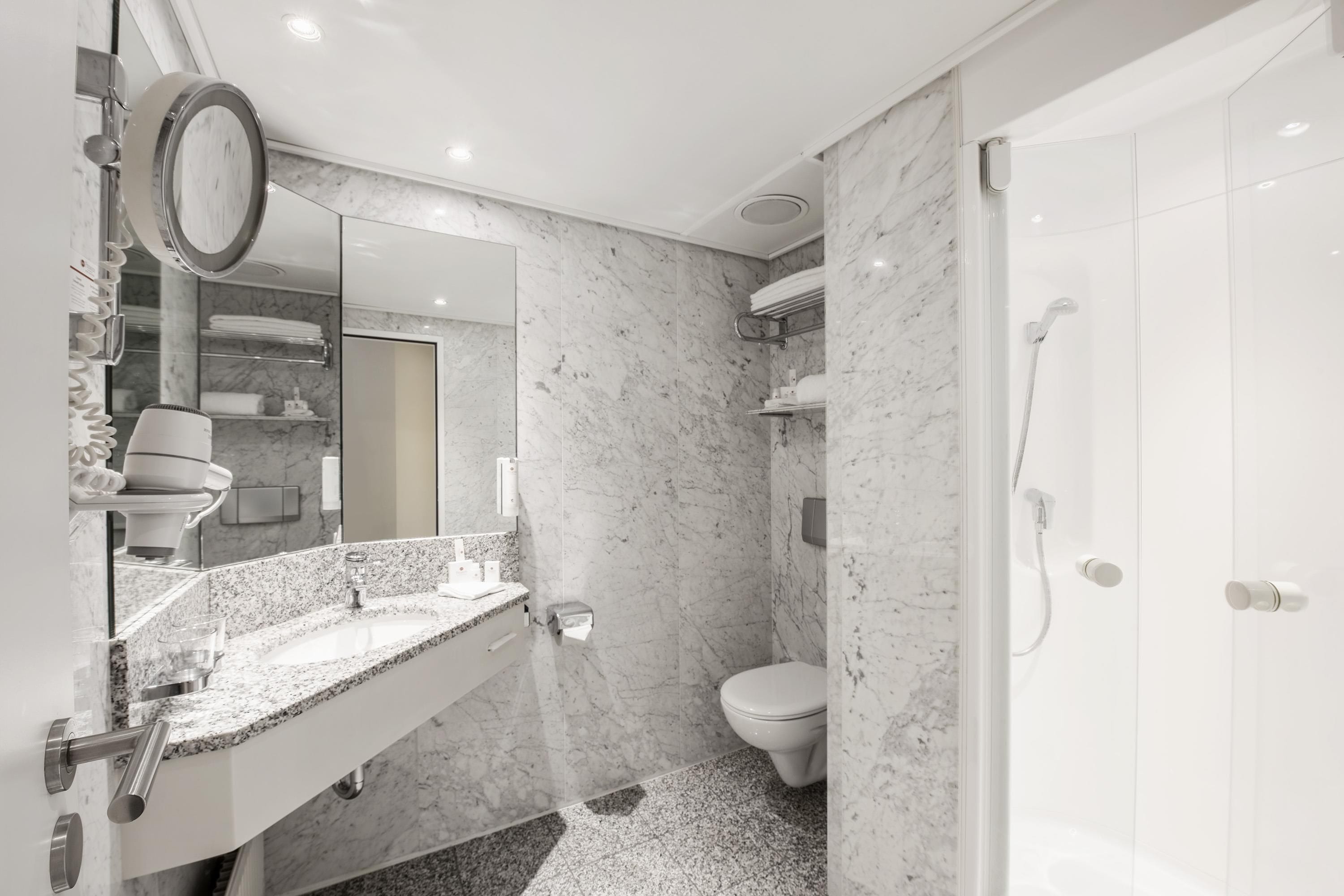 Ein modernes Badezimmer mit Marmorwaschbecken, Toilette und Dusche.