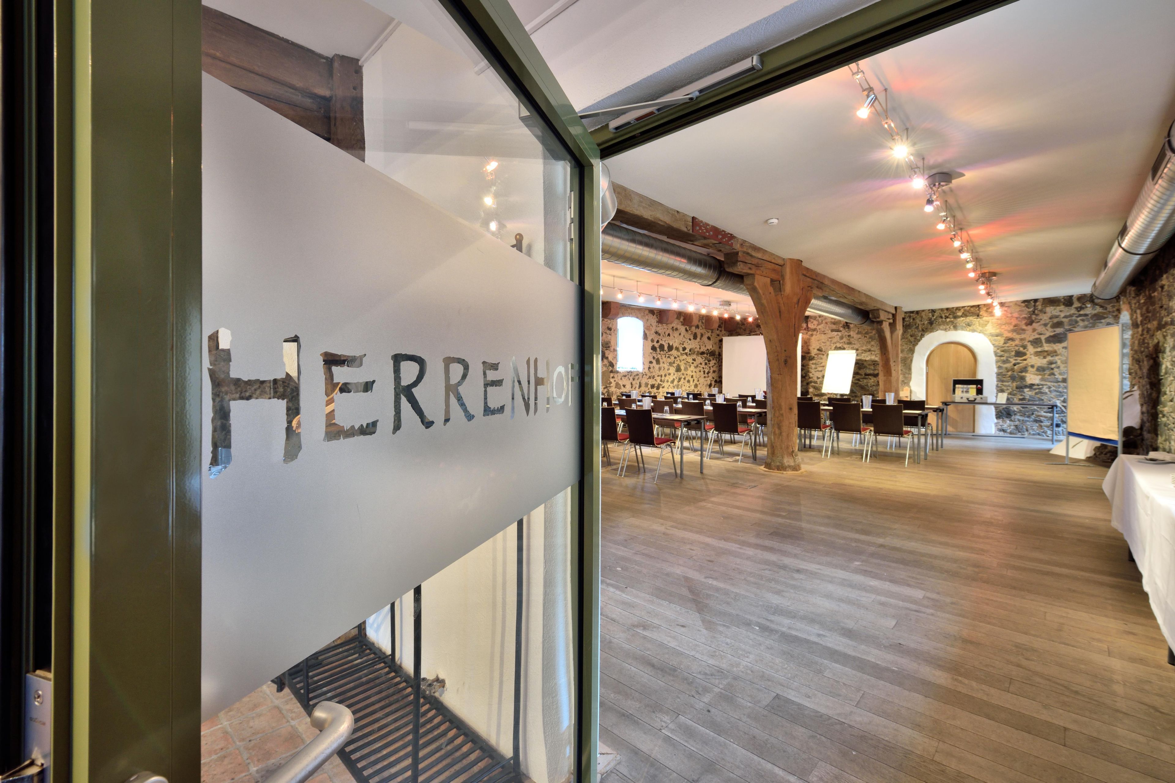 A modern interior with a glass wall displaying the name 'HERRENHAUS'.