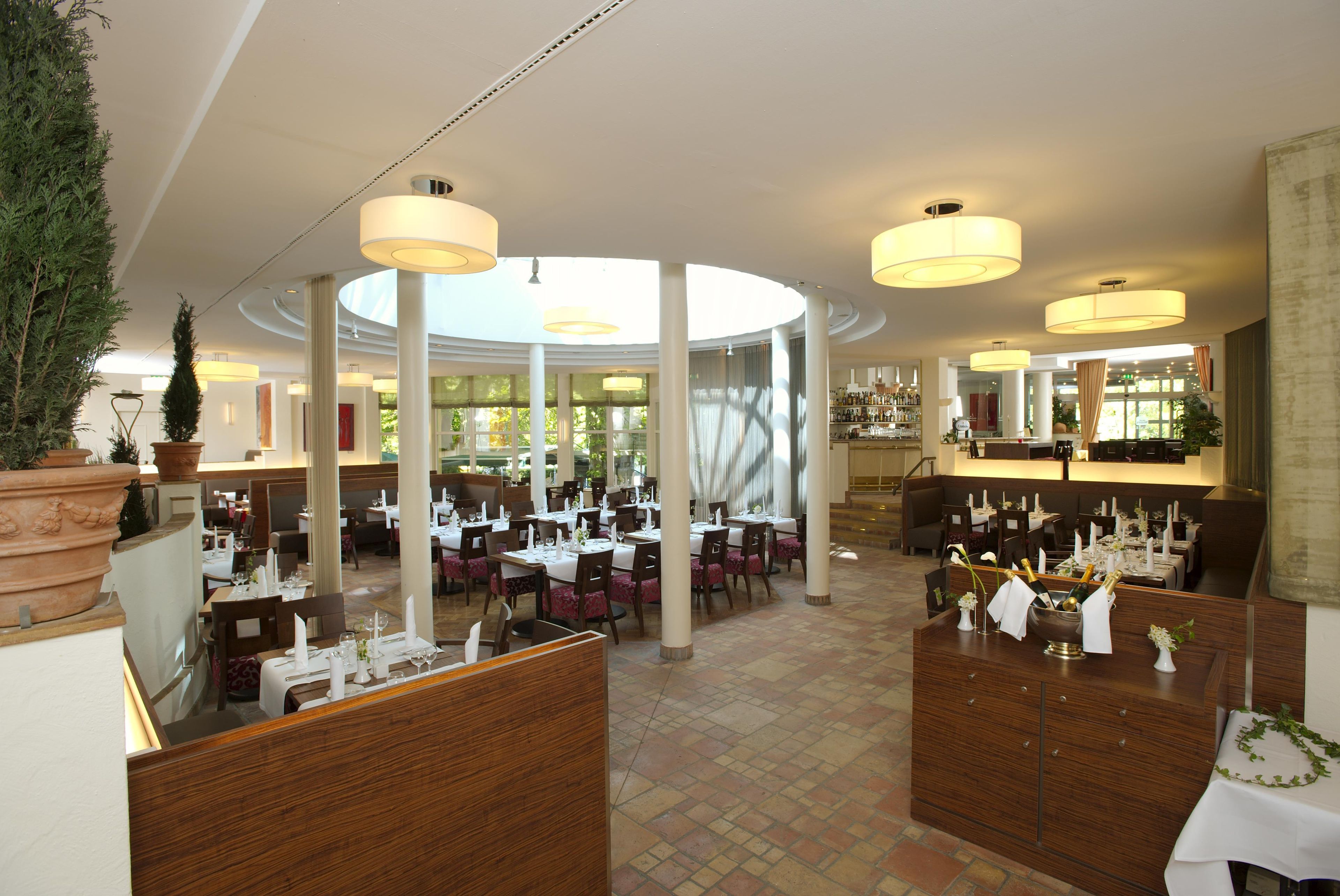 A restaurant with multiple dining areas, large windows, and a central bar.