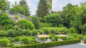 Un jardín ajardinado con una torre de piedra, un sendero y una zona de estar al aire libre.