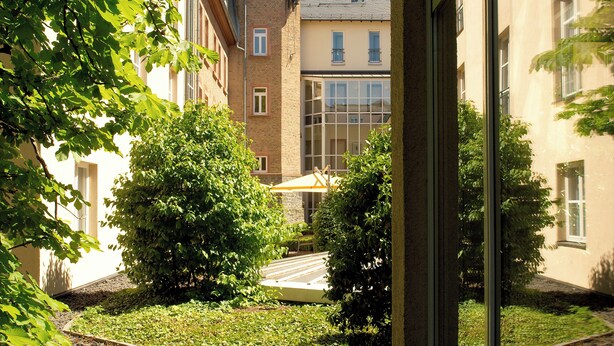 A courtyard with a brick tower, a covered seating area, and a stone pathway.