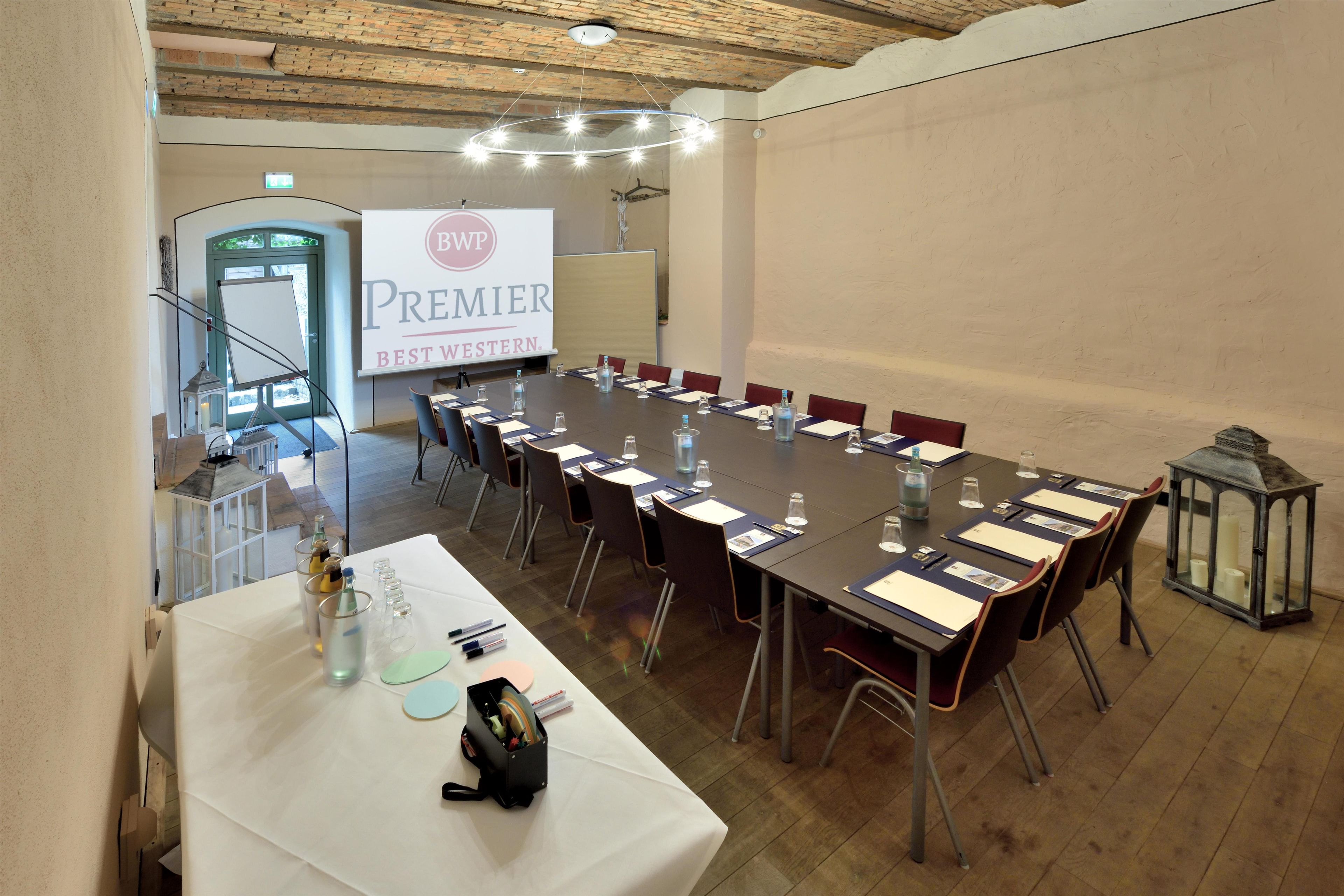 A conference room with a long table, chairs, and a projector screen displaying 'BWP PREMIER BEST WESTERN.'