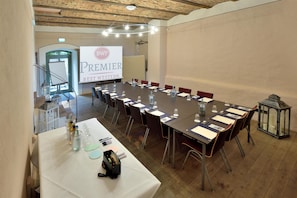 Ein Konferenzraum mit einem langen Tisch, Stühlen und einer Projektionsleinwand, auf der 'BWP PREMIER BEST WESTERN' angezeigt wird.
