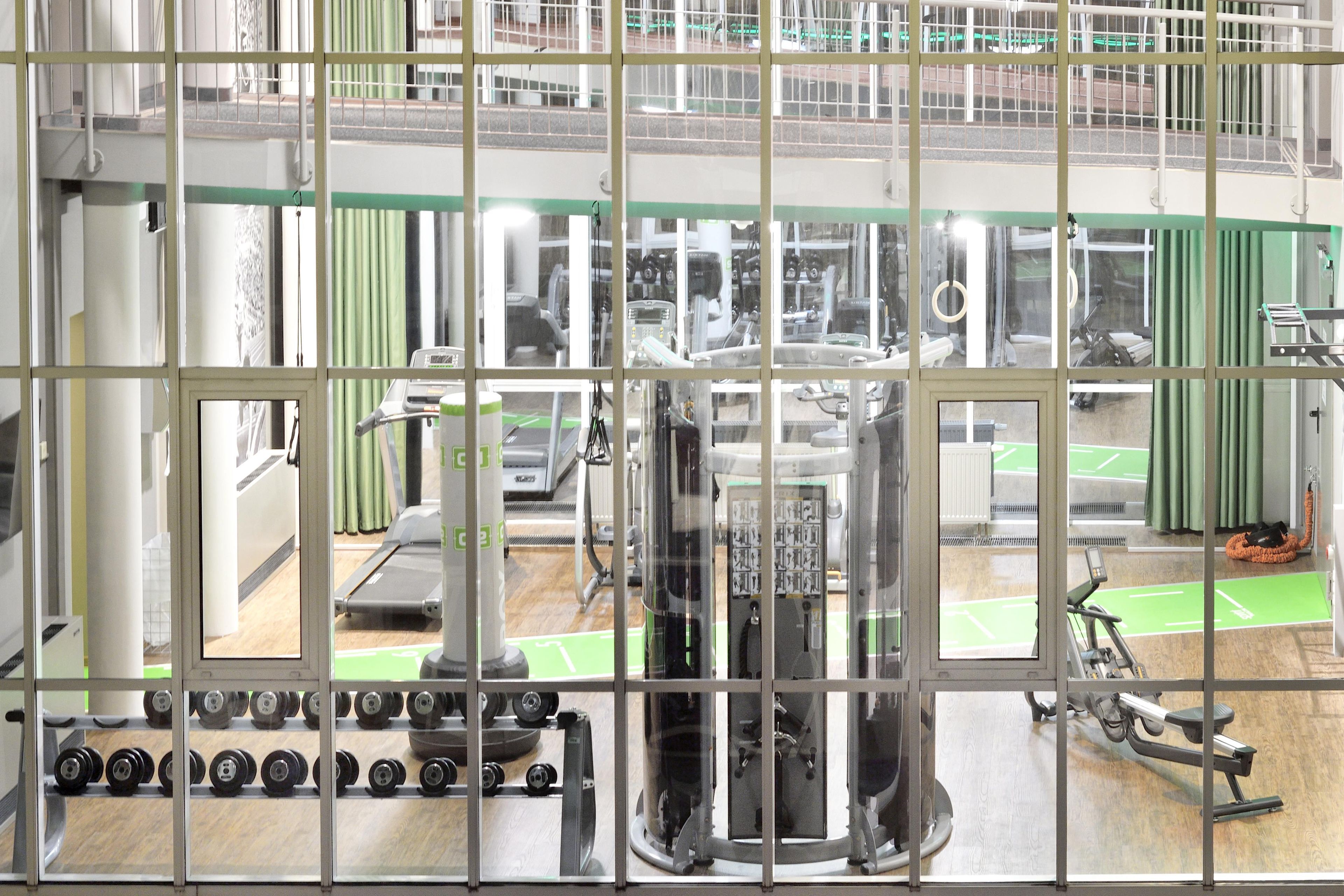 Un gimnasio con equipo de ejercicio diverso, incluyendo cintas de correr, mancuernas y máquinas de pesas.
