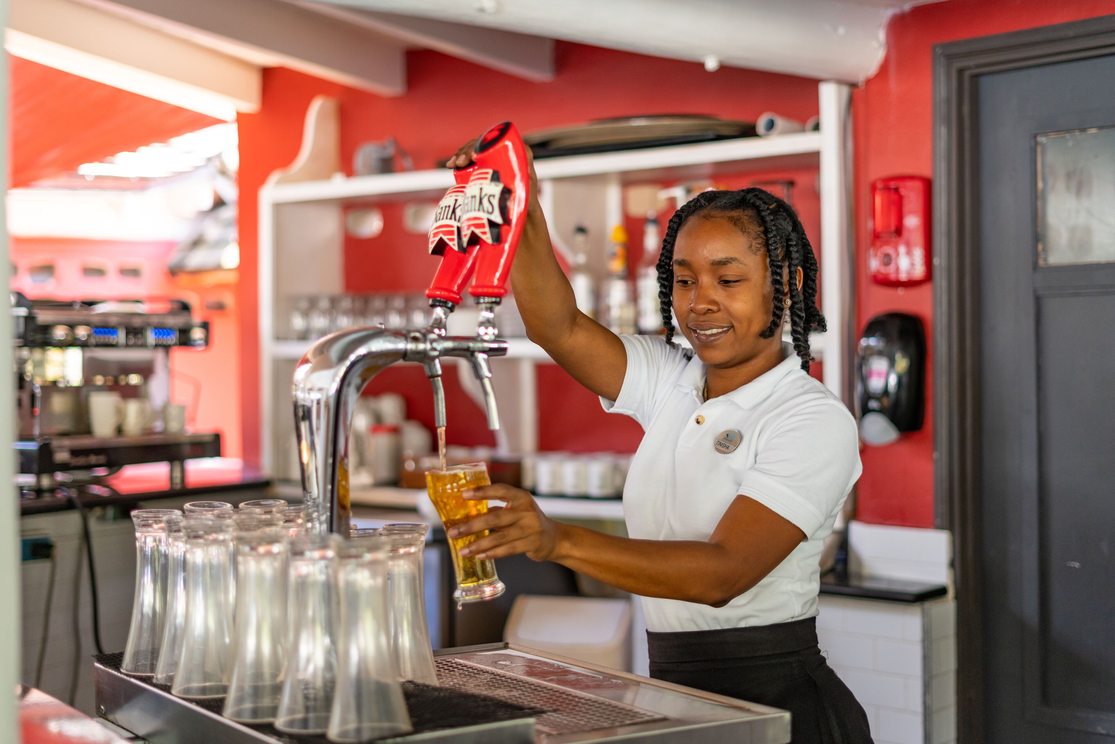 A barista pouring a drink into a glass.