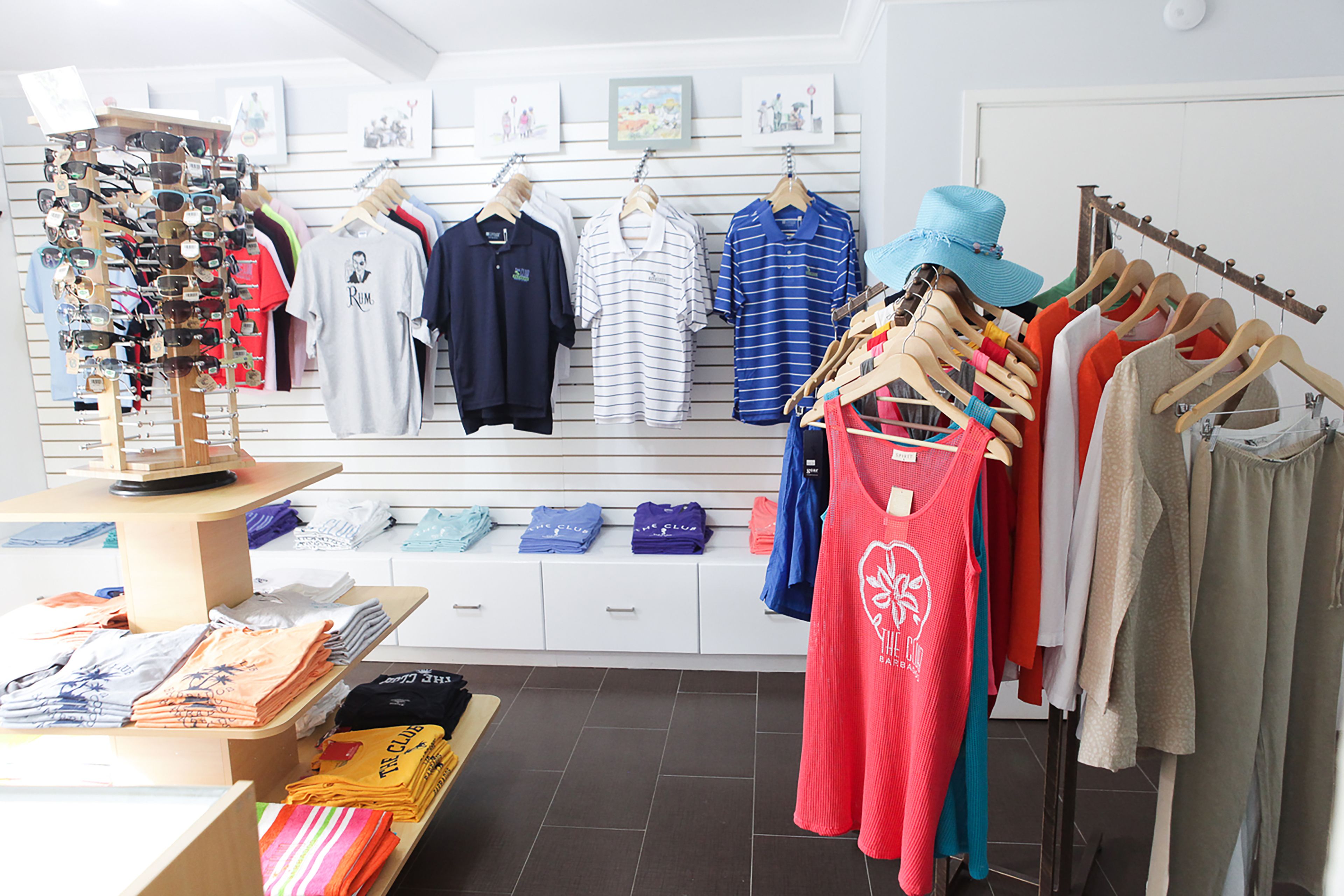 A clothing store with racks of shirts and pants, a display of sunglasses, and a mannequin.