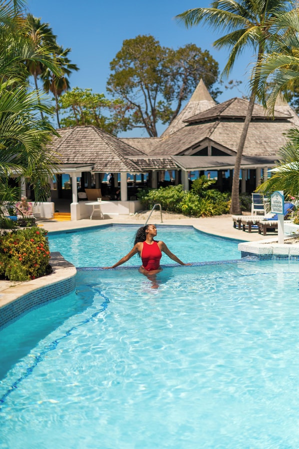 Una piscina al aire libre, sombrillas, sillones reclinables de piscina