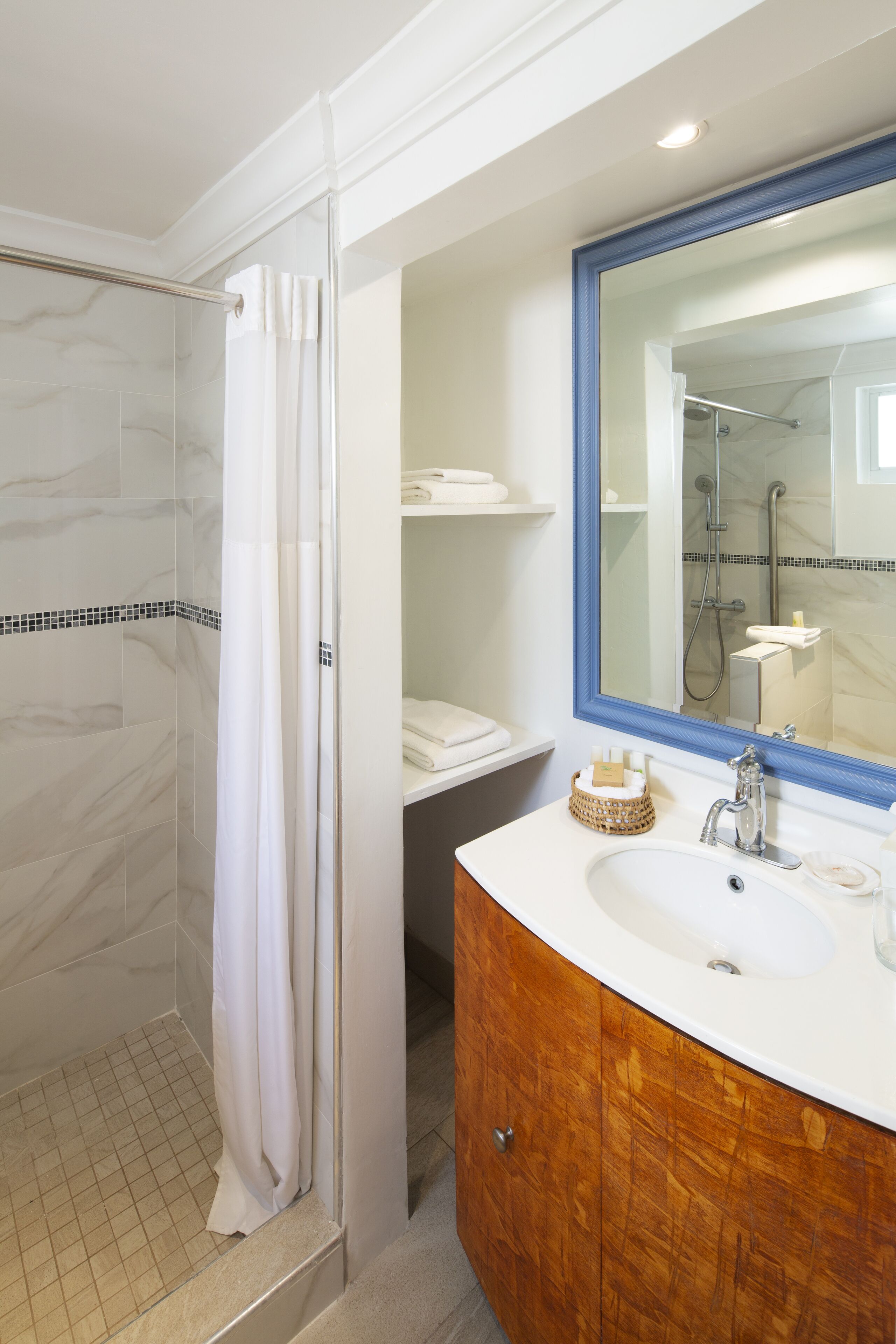 A bathroom with a shower, a sink with a mirror, and a vanity with a wooden cabinet.