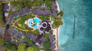 An aerial view of a resort with multiple buildings, a swimming pool, and a beach.