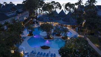 Relax by the pool surrounded by palm trees and lounge chairs.