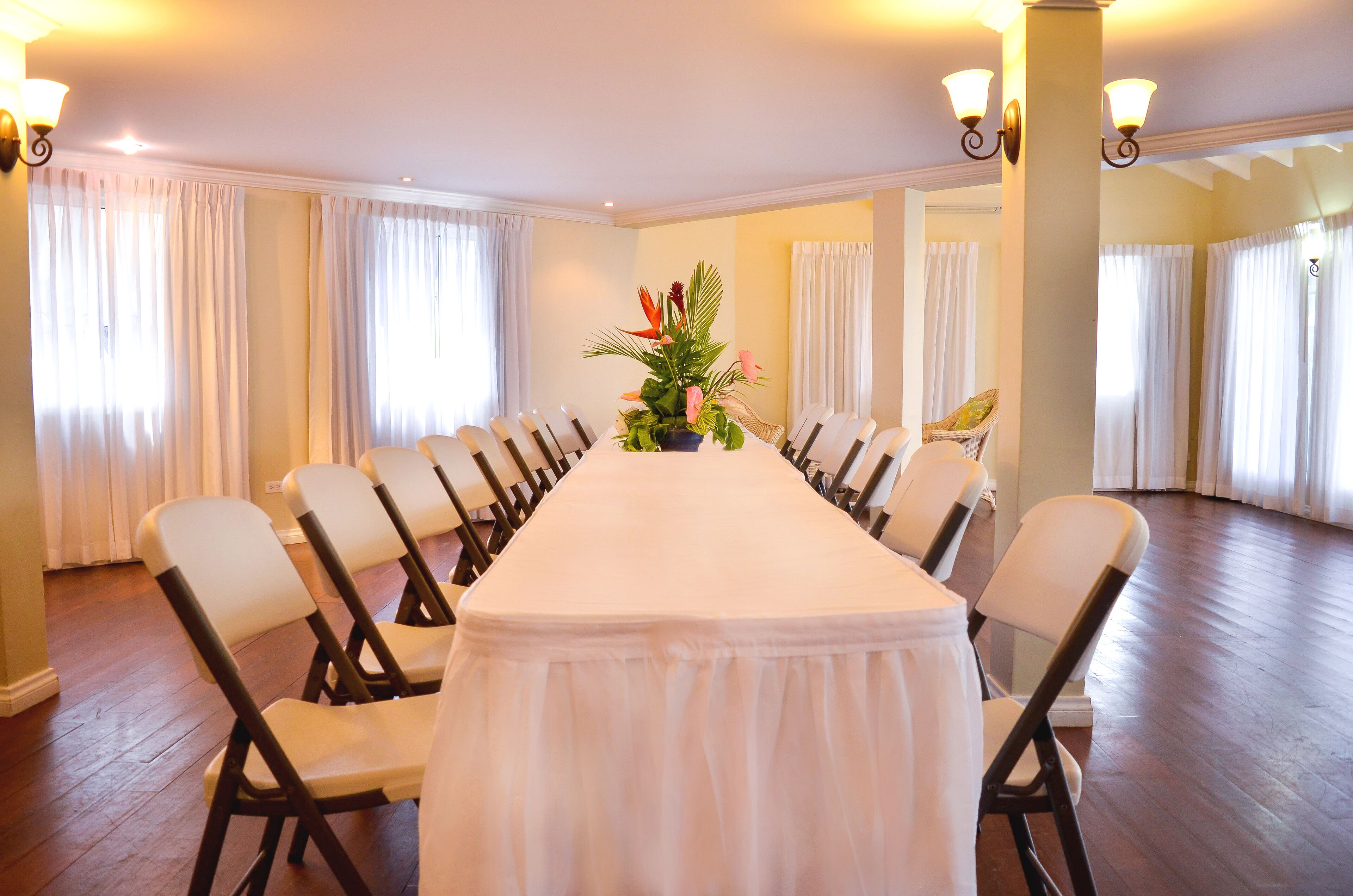 A conference room with a long table, chairs, and a floral centerpiece.