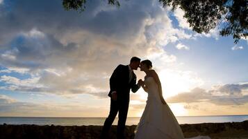 A couple embracing on a beach with a sunset in the background.
