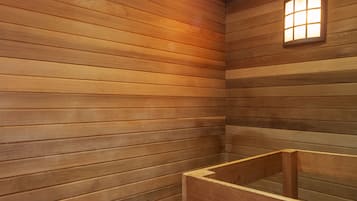 A wooden sauna with benches and a wooden bucket.