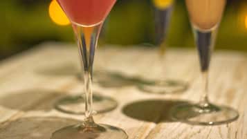 Three drinks in martini glasses on a wooden table with a blurred background.