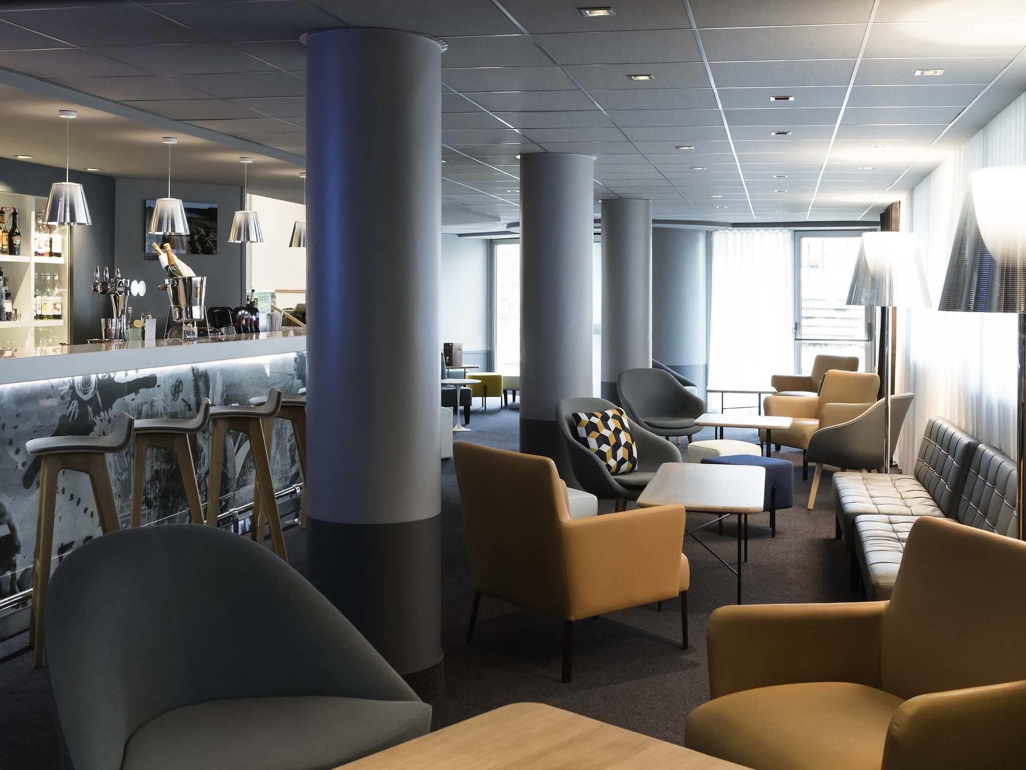 Un'area lounge moderna con soffitti alti, ampie colonne e arredi contemporanei.