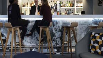 Un espace bar avec des tabourets en bois, un comptoir en marbre et une variété de bouteilles.