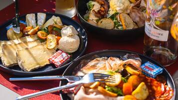 A table with various dishes including cheese, bread, and a salad, along with a bottle of wine.