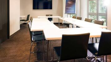 A conference room with a long table, chairs, a projector screen, and a welcome screen.
