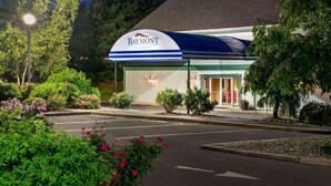 Un hotel Baymont con entrada cubierta, jardín ajardinado y aparcamiento.