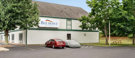 A Baymont motel with a red car parked in front.