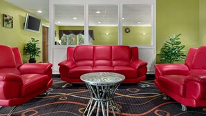 Una habitación con un sofá rojo, una mesita redonda y dos plantas en macetas.