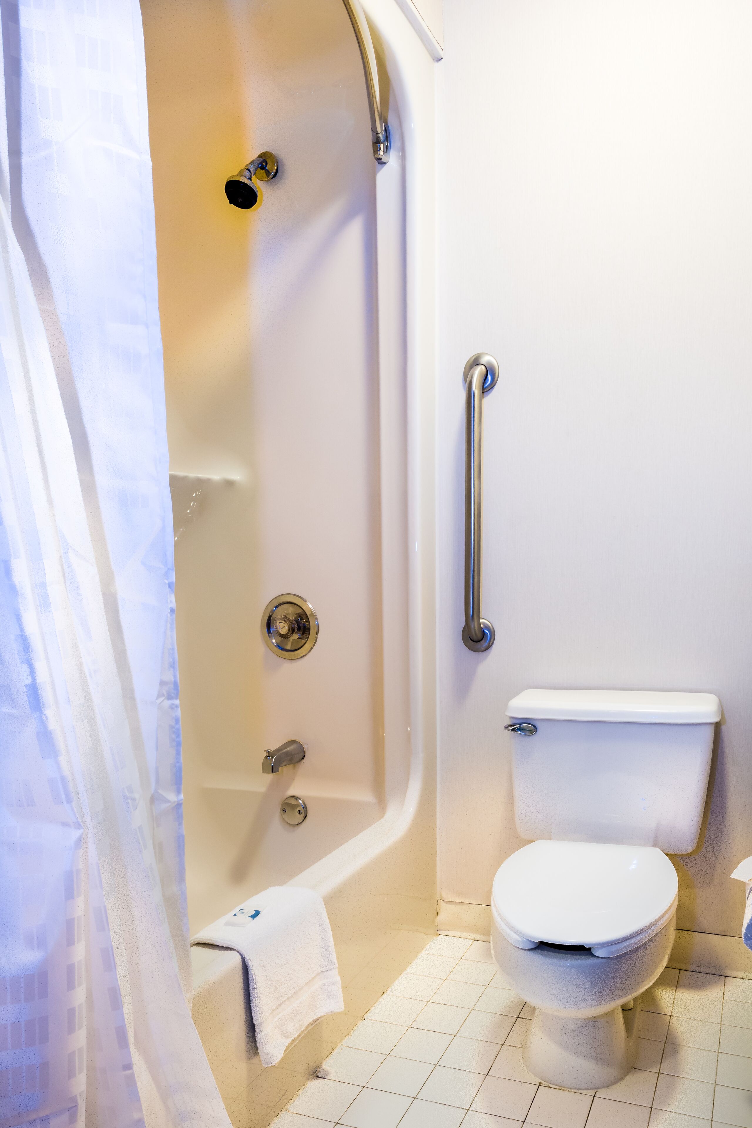 A bathroom with a bathtub, toilet, and grab bar.