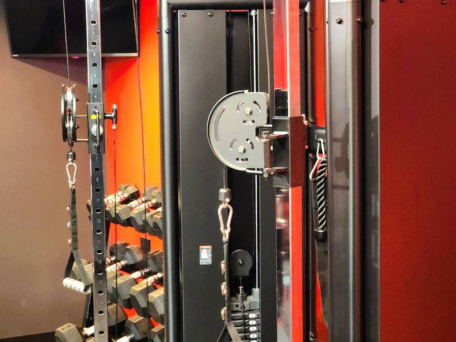 Una palestra con attrezzatura per l'allenamento della forza, inclusa una macchina a cavi e manubri.
