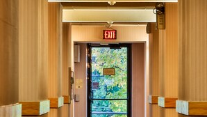 A hotel corridor with an exit sign, a patterned carpet, and wooden paneling on the walls. - The View Inn & Suites (Bethlehem)