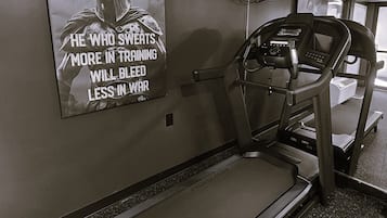 A treadmill in a gym with a motivational poster on the wall.