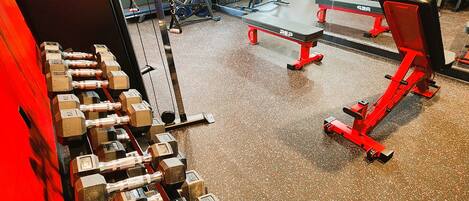 A gym with various exercise equipment, including dumbbells, treadmills, and weight benches.