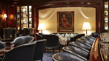 A luxurious bar area with leather seating, a painting on the wall, and a well-lit ambiance.