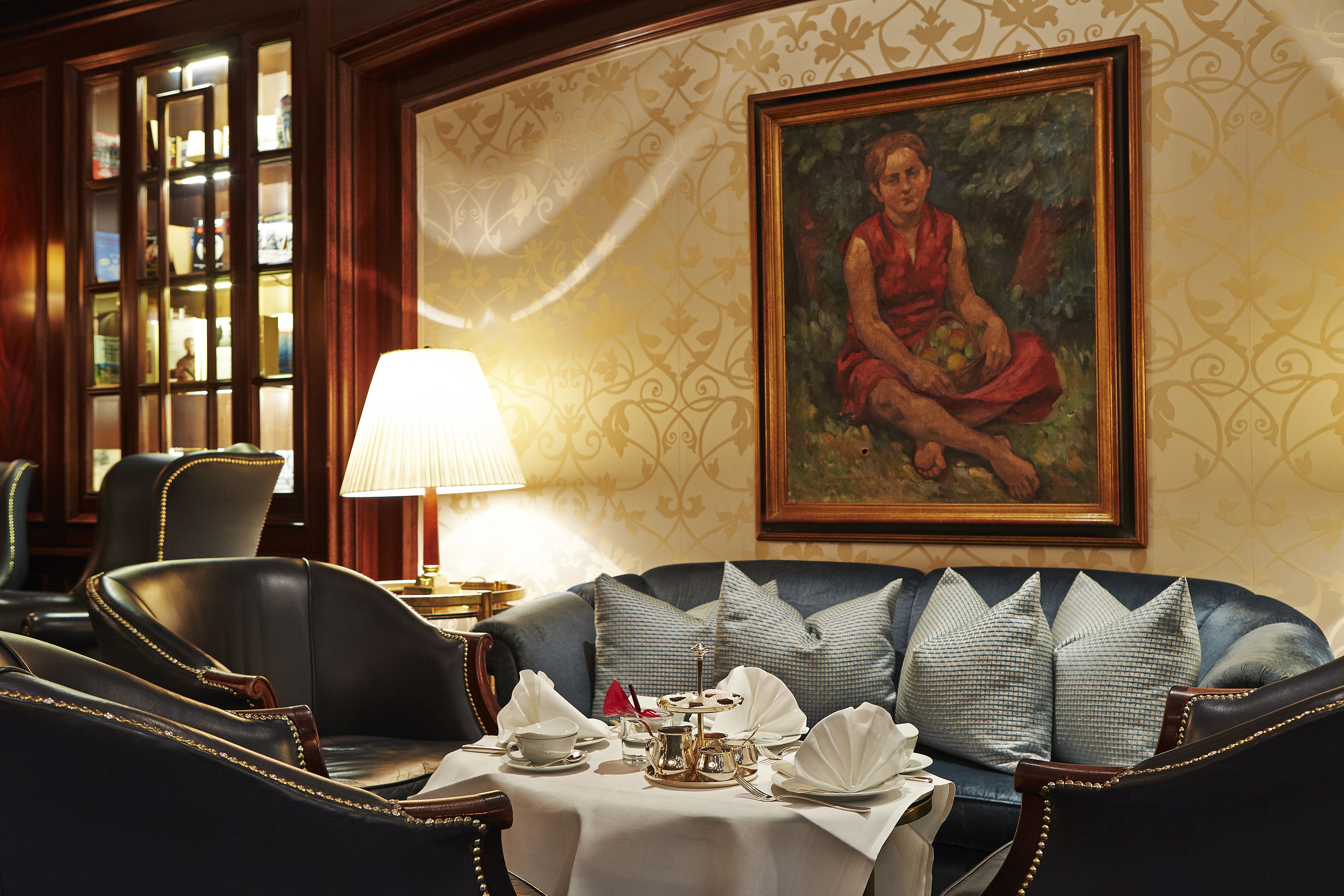 A dining area with a table set for four, a sofa, and a painting on the wall.