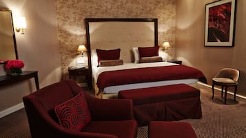 A hotel room with a large bed, two bedside tables, a chair, and a small table with a vase of flowers.