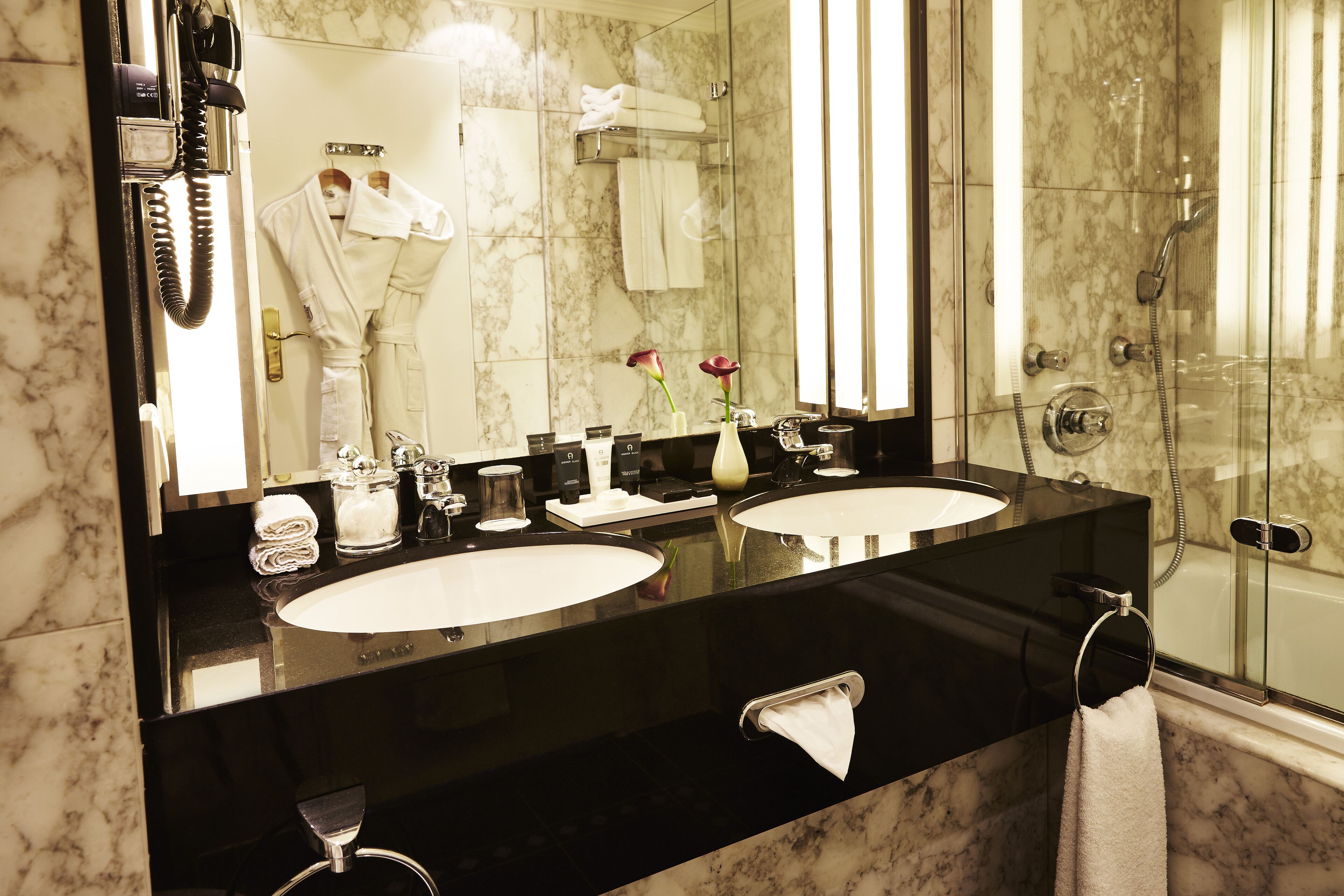 A bathroom with two sinks, a mirror, and a shower.