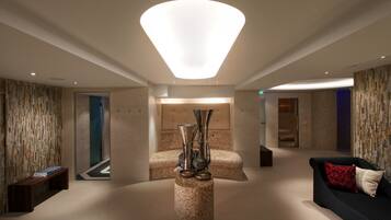 En moderne lobby med et centralt siddeområde, en dekorativ vase og et unikt loftslampe.