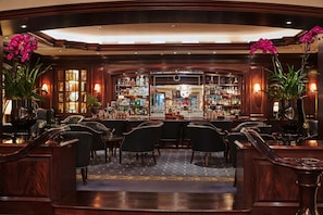 A bar area with wooden furniture, a patterned carpet, and a well-stocked bar.