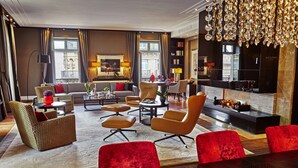 Ein geräumiges Wohnzimmer mit einer Couch, Sesseln, einem Couchtisch und einem Esstisch.