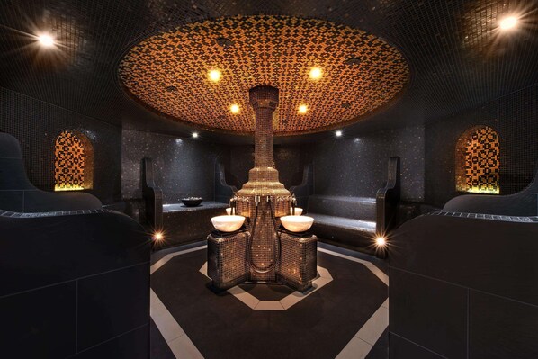 Un spa moderno con una fuente central, zonas de estar y un techo con diseño.