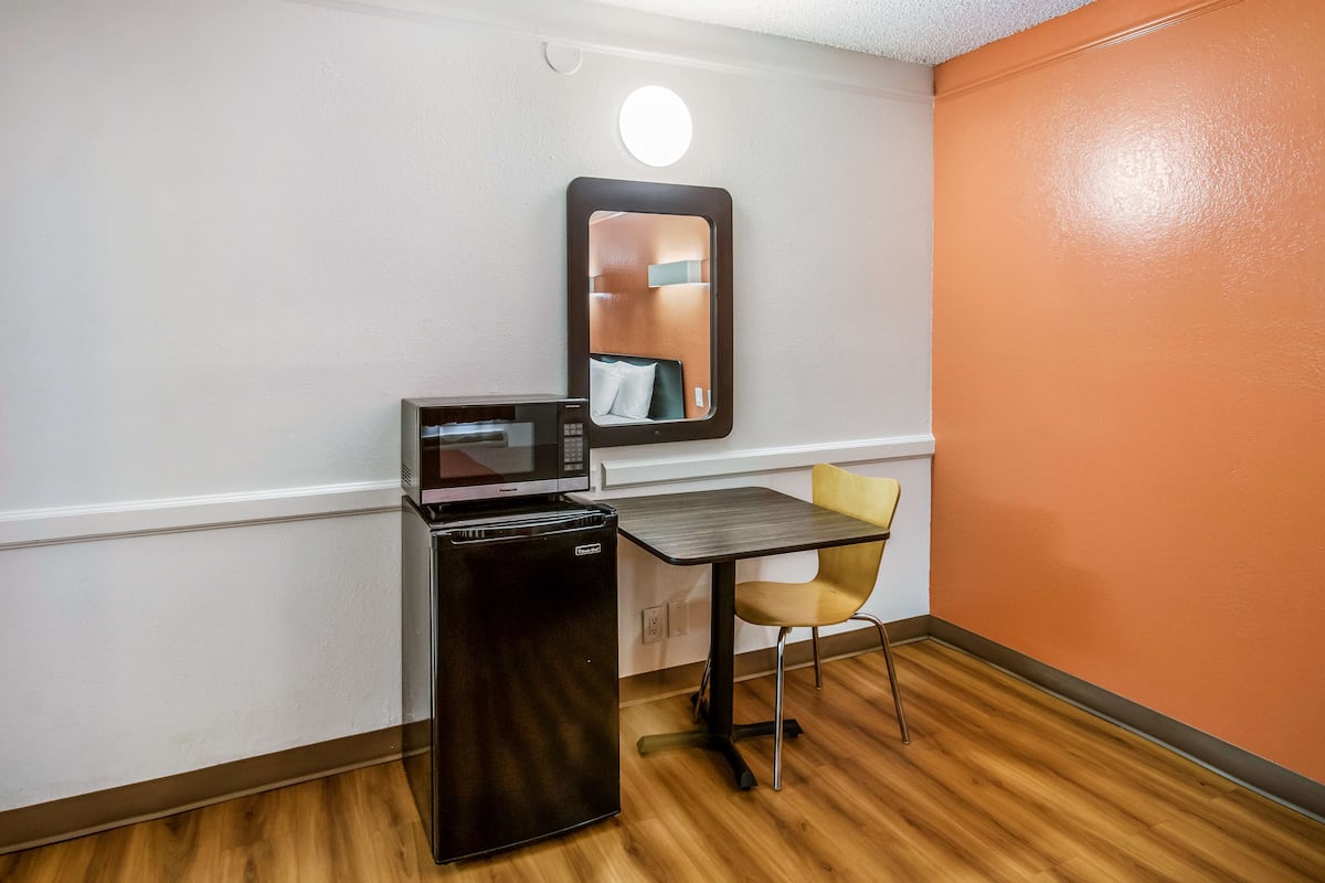 A compact kitchenette with a microwave, refrigerator, and a small table with a chair.