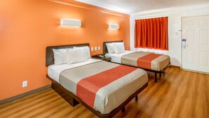 A hotel room with two beds, orange walls, wooden flooring, and a white door. - Motel 6 Euless, TX - DFW West (Euless)