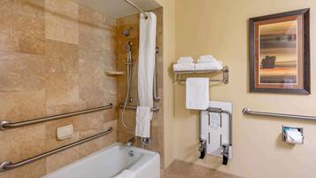 A bathroom with a bathtub, grab bars, a shower, and a towel rack.