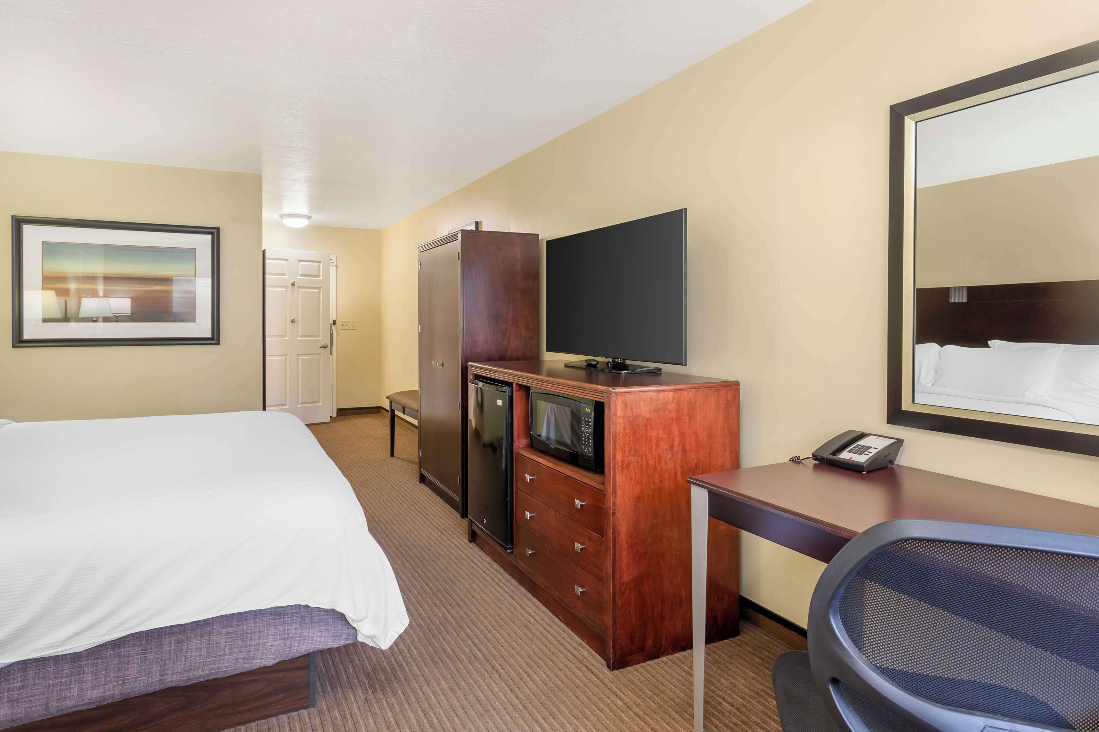 Habitación de hotel con cama, escritorio, teléfono, televisión y minibar.