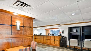 A reception area with a wooden reception desk, a seating area with striped chairs, and a counter with a computer and phone. - Hampton Inn Memphis-Poplar (Memphis)