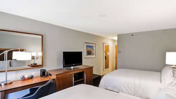 Une chambre d’hôtel avec deux lits, un bureau avec une télévision, une machine à café et un miroir.
