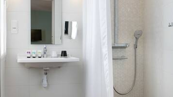Un baño moderno con lavabo, espejo, ducha e inodoro.